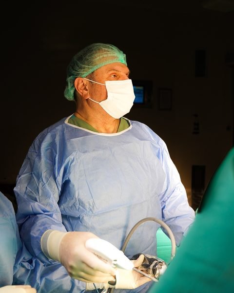 Op. Dr. Kenan Yüce ameliyathanede, steril önlük ve maskeyle.